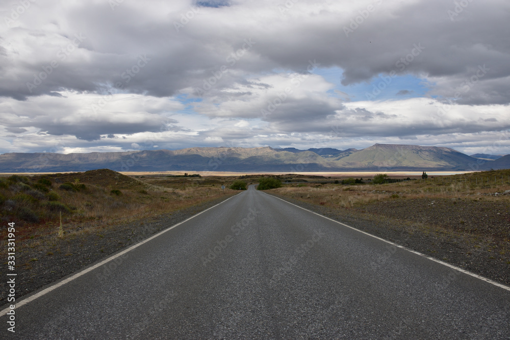 Ruta de asfalto con lago montagnas y cielo con nubes en patagonia argentina