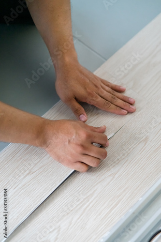 A person installing new vinyl tile floor, a DIY home project. © ellinnur