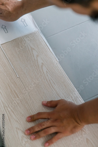 A person installing new vinyl tile floor, a DIY home project.