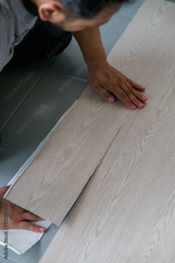 A person installing new vinyl tile floor, a DIY home project. A person installing new vinyl tile floor, a DIY home project.