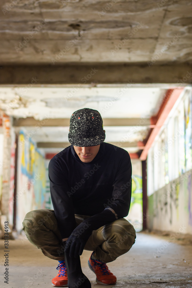 Young man wearing a cap in a ruined building full of graffiti
