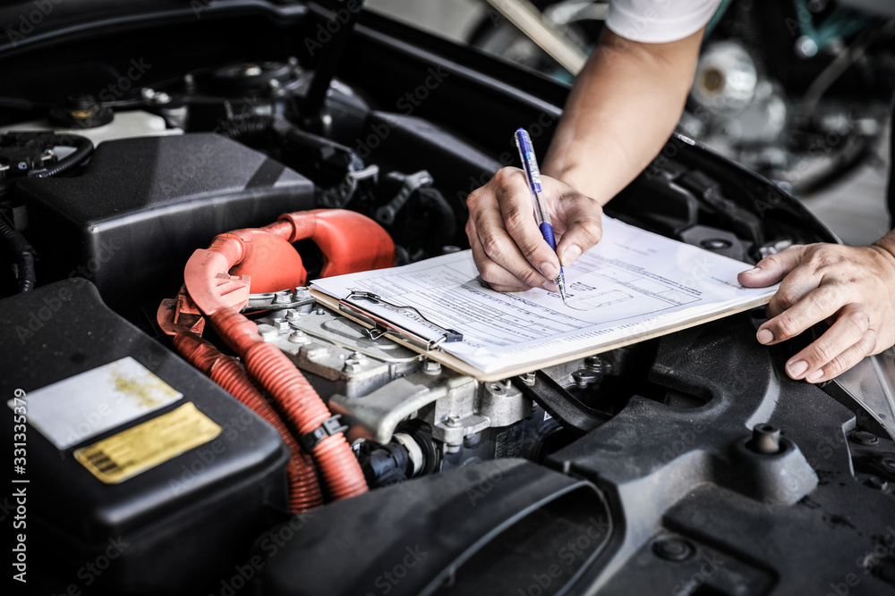 Worker checking document in front of the automotive maintenance