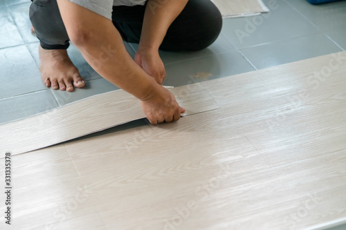 A person installing new vinyl tile floor, a DIY home project.