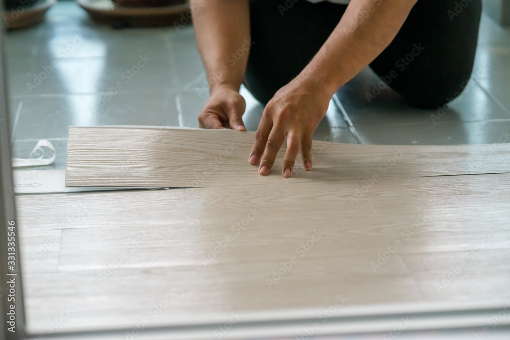 A person installing new vinyl tile floor, a DIY home project. A person installing new vinyl tile floor, a DIY home project.