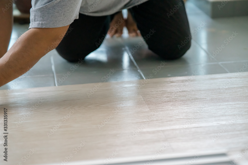 A person installing new vinyl tile floor, a DIY home project. A person installing new vinyl tile floor, a DIY home project.