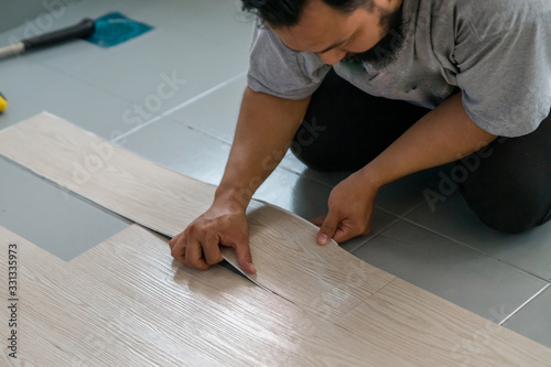 Photography Kuala Lumpur, Malaysia - March 1, 2020: A man installing new vinyl tile floor, a DIY home project
