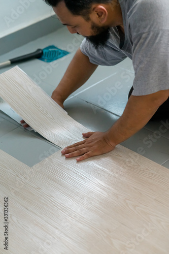 Kuala Lumpur, Malaysia - March 1, 2020: A man installing new vinyl tile floor, a DIY home project.