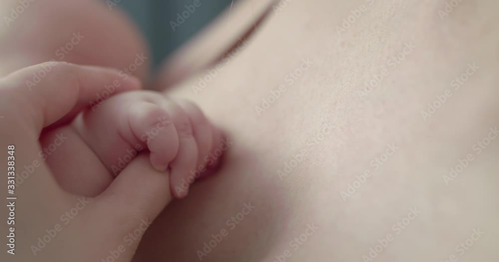 Little baby's hand in mother's hand during breastfeeding Little baby's hand in mother's hand during breastfeeding