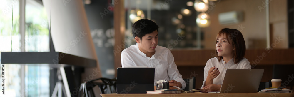 Cropped shot of two businesspeople discussing on their work with computer laptop Cropped shot of two businesspeople discussing on their work with computer laptop