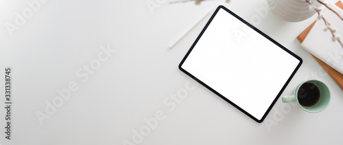 Top view of workspace with blank screen tablet, office supplies, coffee mug and copy space