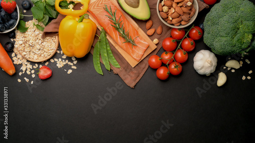Top view of Healthy food clean eating selectionassortment with salmon, fruits, vegetable, seeds and copy space on black table