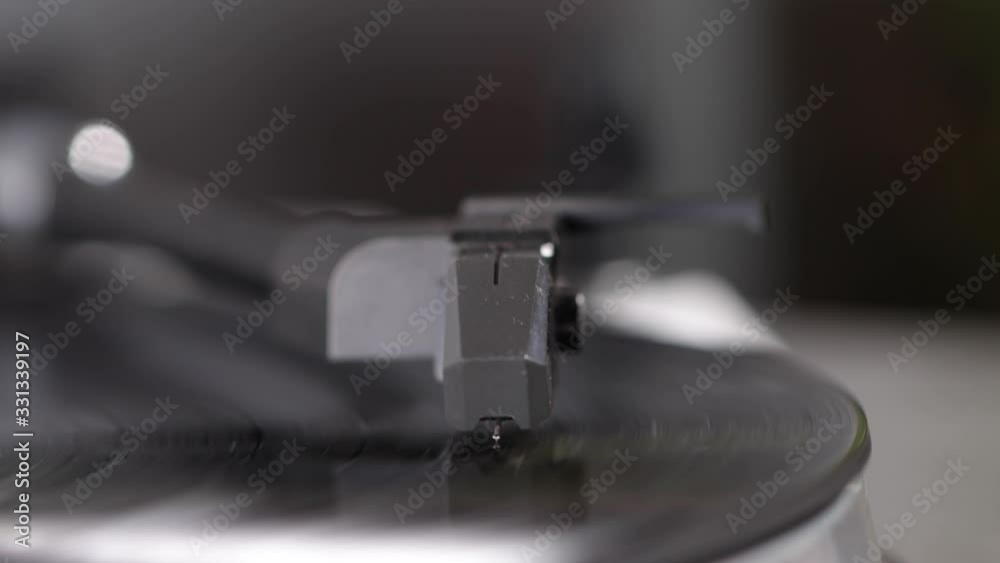 Close up of turntable needle on a vinyl record. Turntable playing vinyl. Needle on rotating black vinyl.
