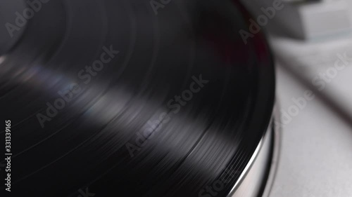 Close up of turntable needle on a vinyl record. Turntable playing vinyl. Needle on rotating black vinyl. photo