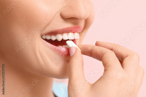 Fototapeta Naklejka Na Ścianę i Meble -  Young woman with chewing gum on color background, closeup
