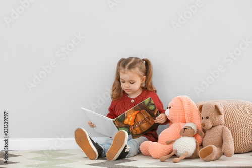 Cute little girl reading bo...