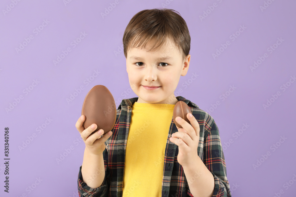 Cute little boy with sweet chocolate eggs on color background Cute little boy with sweet chocolate eggs on color background