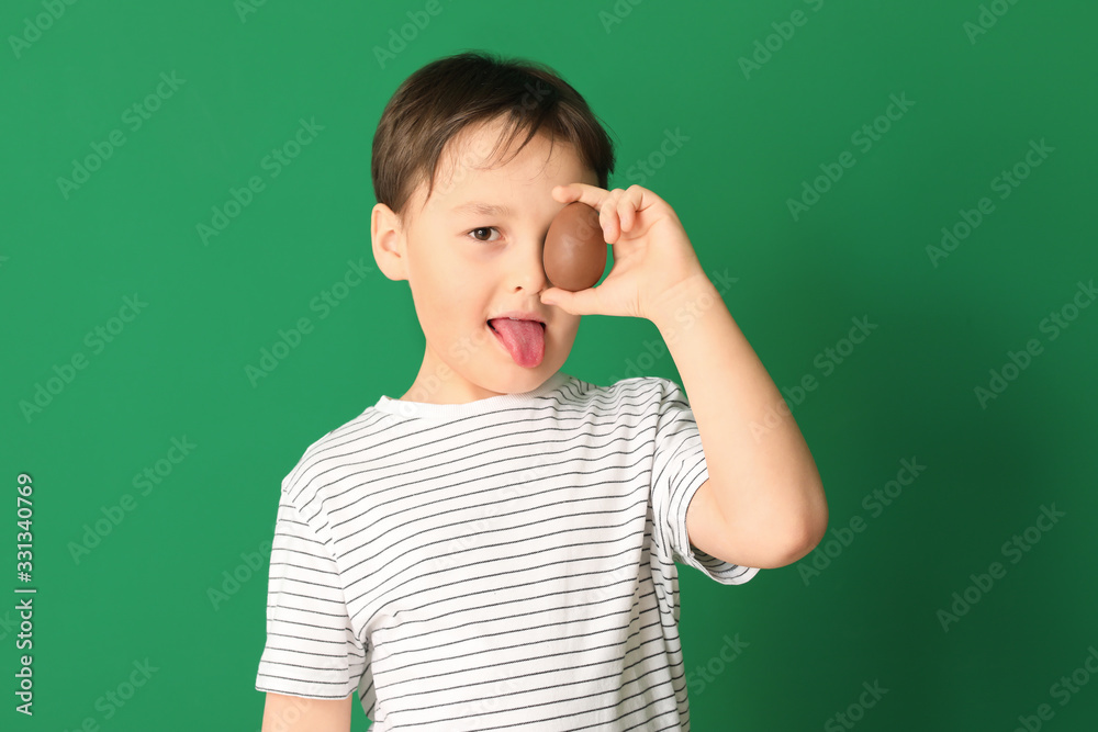 Cute little boy with sweet chocolate egg on color background Cute little boy with sweet chocolate egg on color background