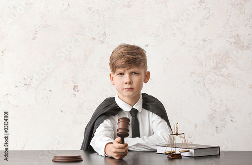 Portrait of little judge sitting at table against white background photo