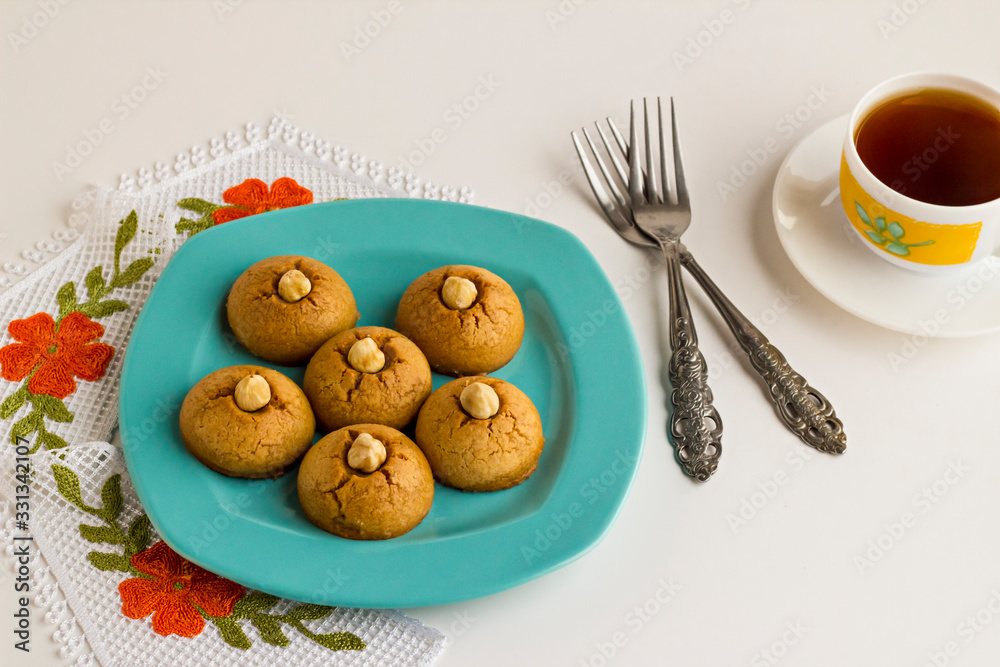 Traditional Turkish Pastry Dessert,Sekerpare in blue plate on white with fork and a cup of tea. Traditional Turkish Pastry Dessert,Sekerpare in blue plate on white with fork and a cup of tea.