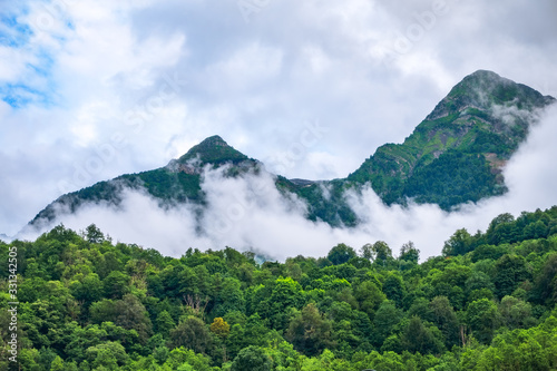 High mountain with green slopes hidden in clouds and fog.