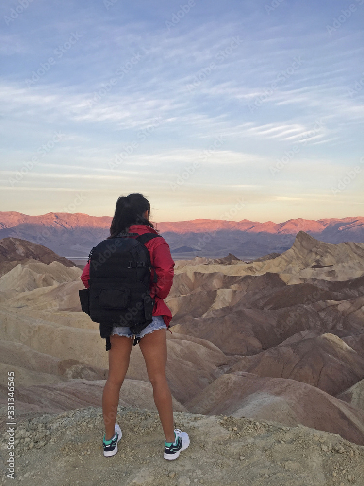 Woman watching beautiful sunrise from Zabriskie Point at Death Valley National Park in California USA