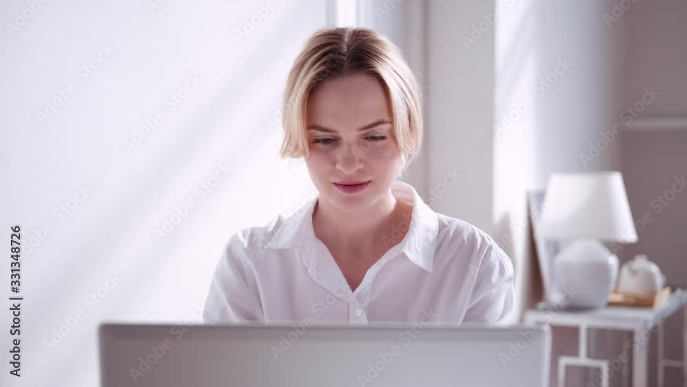 Modern blonde woman in a sunny room working with laptop, portrait Modern blonde woman in a sunny room working with laptop, portrait