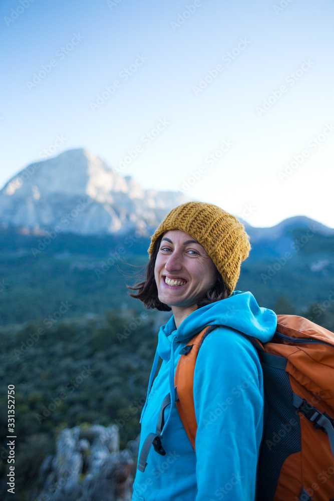 Portrait of a smiling girl with a backpack on a background of mountains.