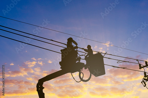 silhouette maintenance of electricians work with high voltage electricity on the hydraulic bucket