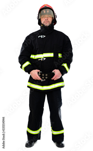 Full-length portrait of a man in black uniform of a fireman with a red helmet on a white isolated background. The model stands right in front of the camera. Studio photo.