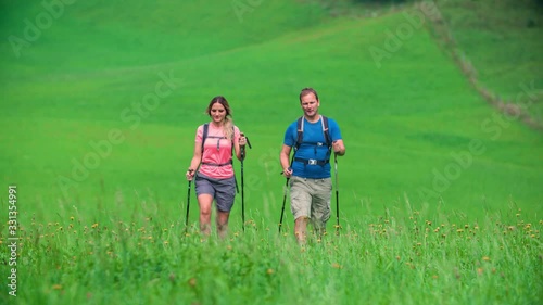 Clip of a couple that walk across a mountain meadow during an excursion. Trekking nordic walking video shot in Topla Valley, Crna na Koroskem, Slovenia photo