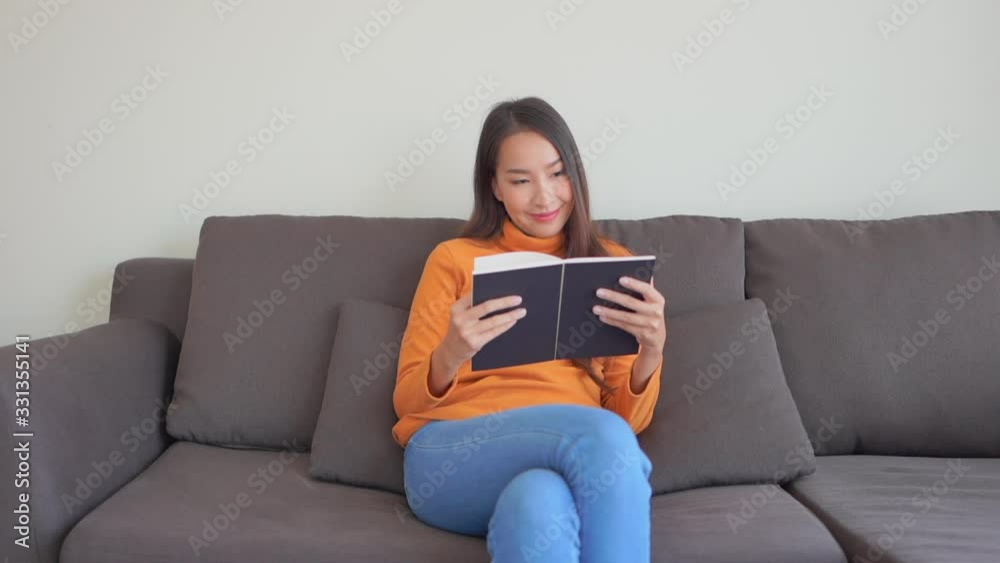 A young attractive Asian woman relaxes with a book on the couch. A young attractive Asian woman relaxes with a book on the couch.