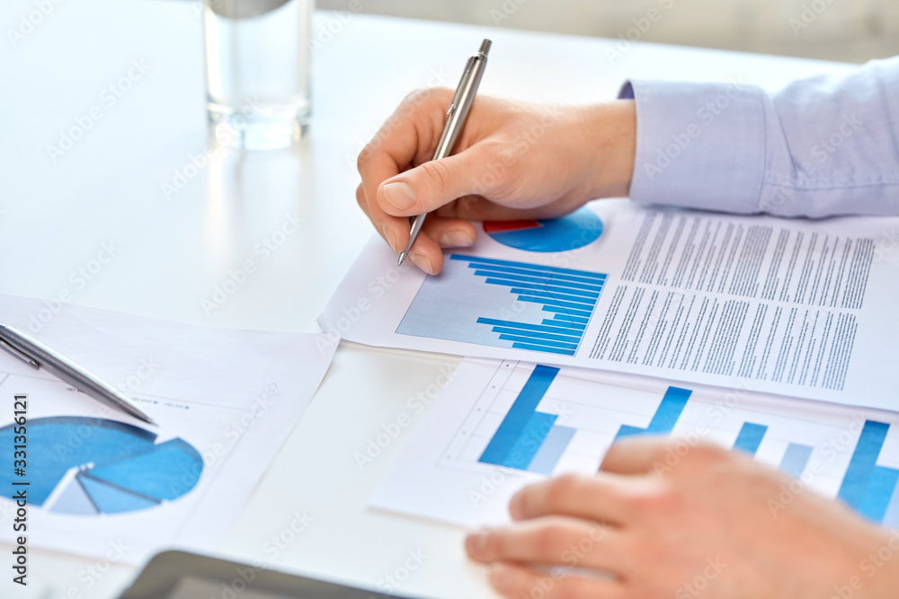 business, corporate and people concept - close up of businessman's hands with pen and charts at office business, corporate and people concept - close up of businessman's hands with pen and charts at office