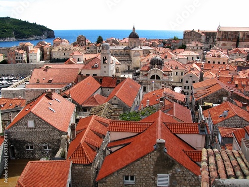 view of the old city of Dubrovnik on a clear summer day, you can see many houses with red roofs, the old Cathedral and the sea