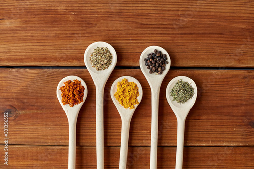 food, culinary and unhealthy eating concept - spoons with different spices on wooden table