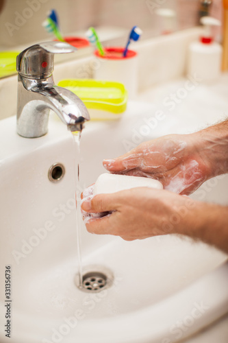 Man washing hands with soap in bathroom. People and healthcare concept.