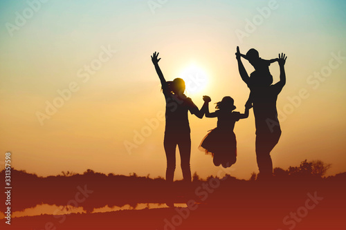 Silhouette of a family comprising a father, mother and two children happy family the sunset.Concept of friendly 