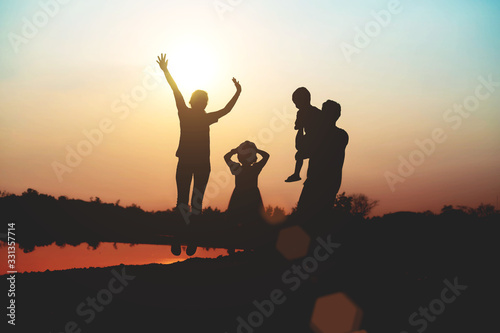 Silhouette of a family comprising a father, mother and two children happy family the sunset.Concept of friendly 