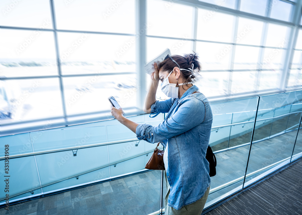 Coronavirus outbreak travel restrictions. Traveler with mask at airport affected by travel ban and flight cancellations and Borders shutdowns. Coronavirus outbreak travel restrictions. Traveler with mask at airport affected by travel ban and flight cancellations and Borders shutdowns.