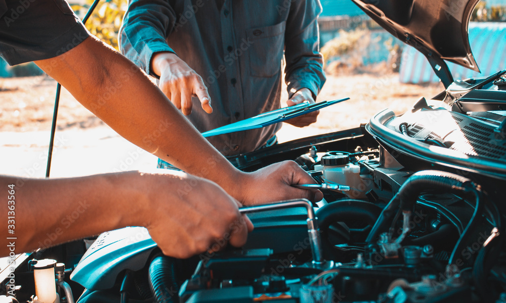 The owner of the garage and the mechanic check the customer's car,Car maintenance concept The owner of the garage and the mechanic check the customer's car,Car maintenance concept