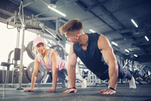 Man and woman strengthen hands at fitness training. Fitness young people doing pushups in a gym looking face happy exercise