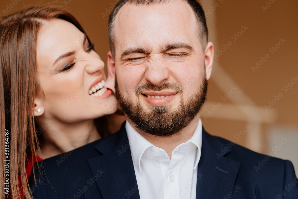 girl in red dress and man in suit and bites on ear girl in red dress and man in suit and bites on ear