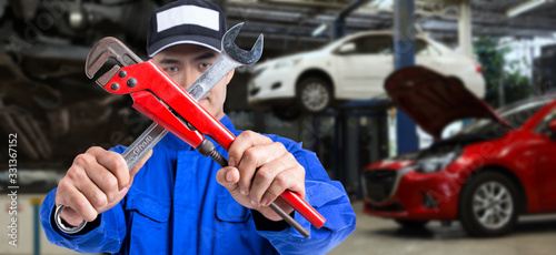 The mechanic with the arms of the cross with a automotive maintenance is background.