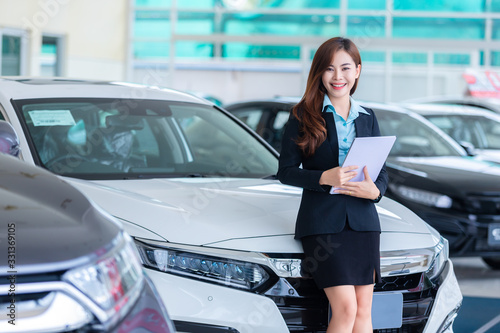 Asian young woman in a car Rental Service Assistant/Car sales concept in show room.