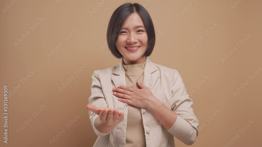 Asian business woman looking at camera happy smiling and say thank you by sign language isolated over beige background. 4K video