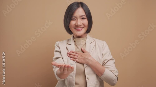 Asian business woman looking at camera happy smiling and say thank you by sign language isolated over beige background. 4K video