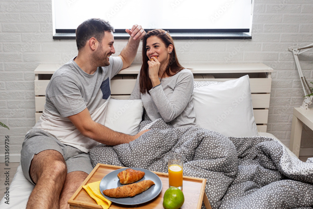 Beautiful happy couple in the morning with breakfast in bed