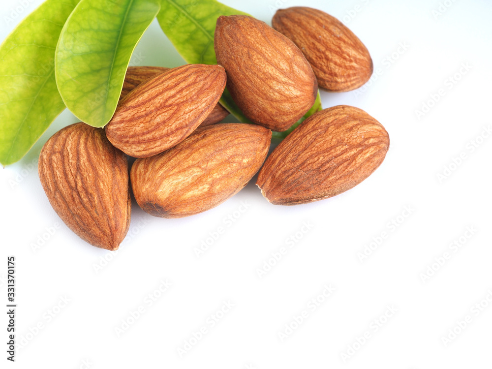 A pile of almonds seed with leaves isolated on a white background. A pile of almonds seed with leaves isolated on a white background.