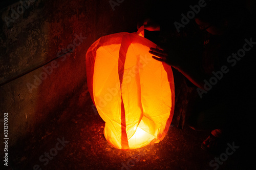 Red Sky lantern with the flames showing clearly held on the ground photo