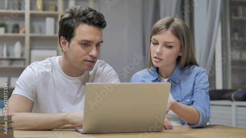 Young Casual Designers Discussing Project and Working On Laptop