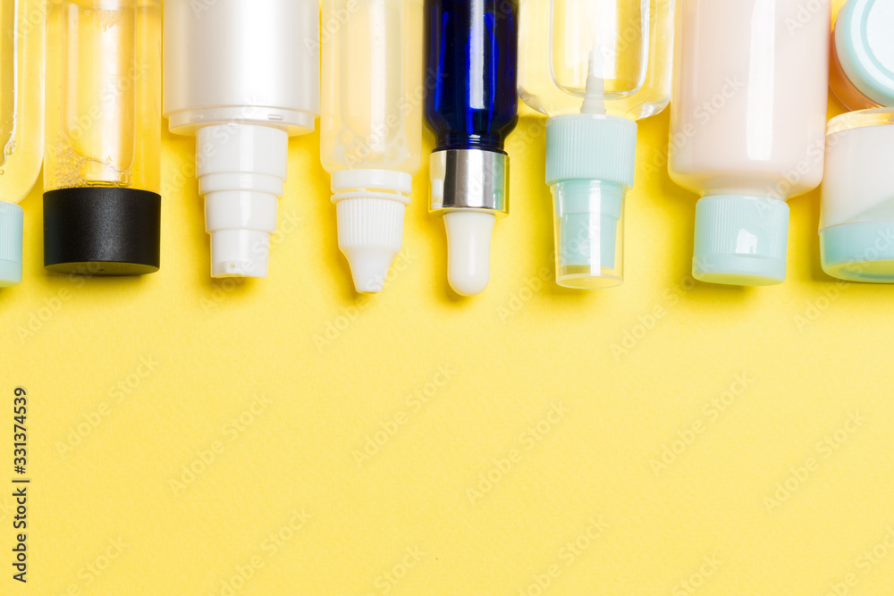Flat lay composition with cosmetic and cream bottles on yellow background. Beauty products concept with copy space Flat lay composition with cosmetic and cream bottles on yellow background. Beauty products concept with copy space